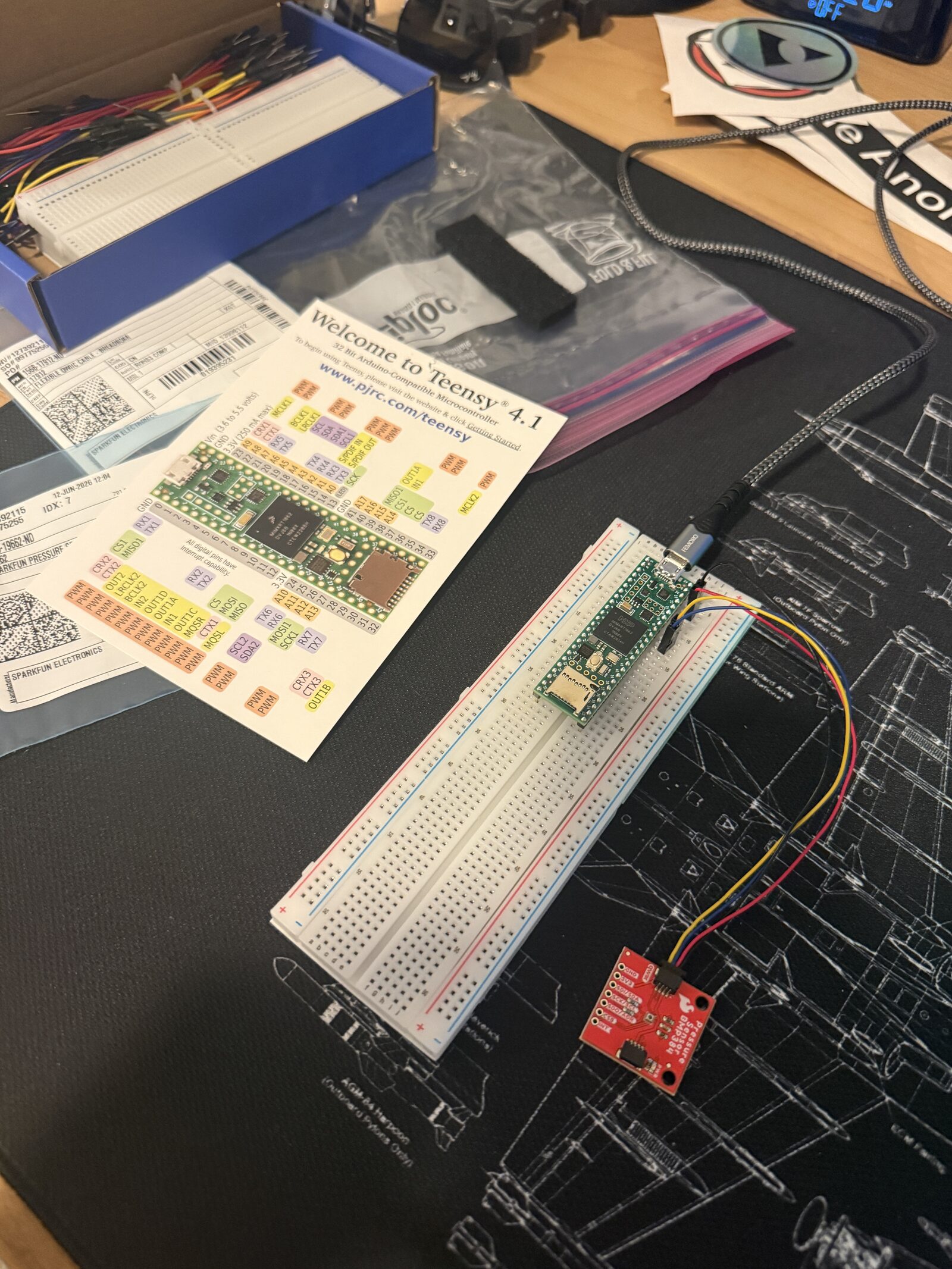 Teensy 4.1 on a breadboard with a BMP384 barometric sensor connected over jumper wires, on a blueprint mat